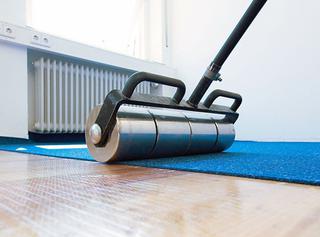 Nadat de nieuwe vloerbedekking – hier een tapijt – middels de verwijderbare lijm gefixeerd is op de ondergrond, wordt die nog even aangewalst